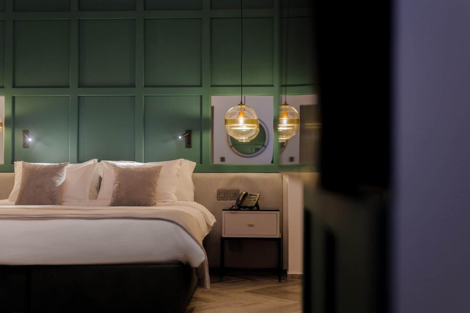 Un dormitorio con cama, mesitas de noche y lámparas fijadas en la pared.