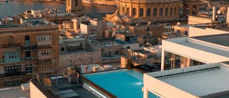 Una piscina en la azotea con vistas despejadas del paisaje urbano, incluyendo un edificio con una cúpula destacada y una torre alta.