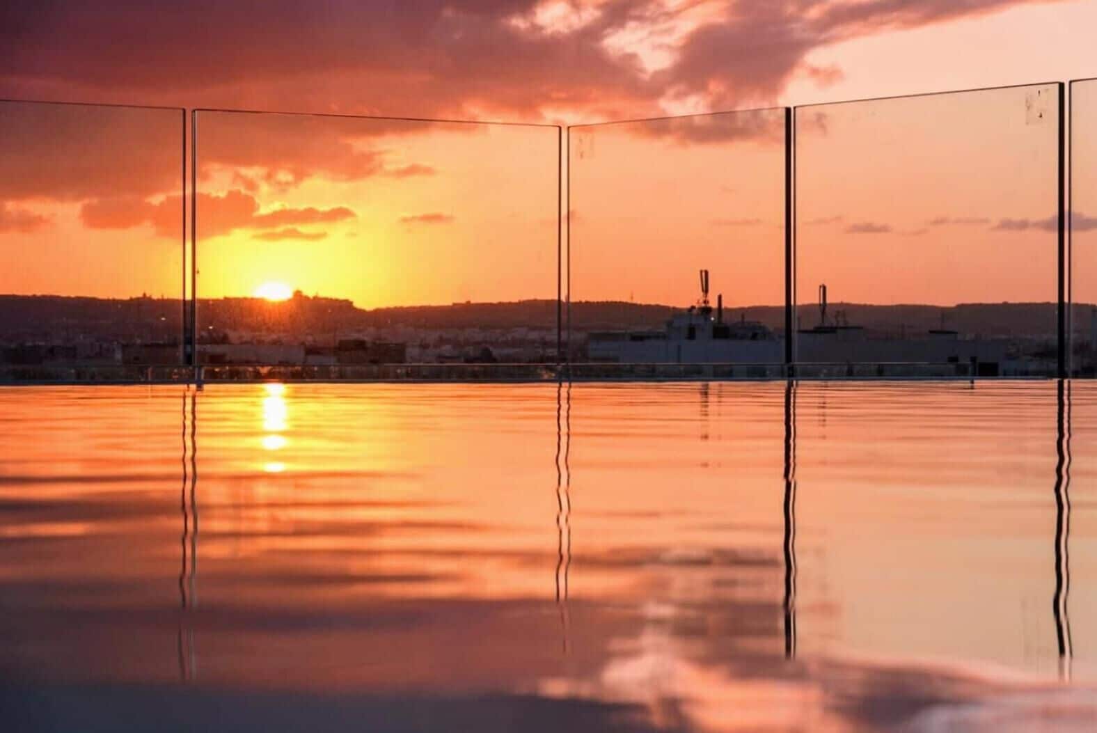 A sunset over a calm body of water with a cityscape in the background.