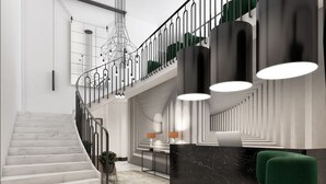 Un vestíbulo moderno con una escalera de mármol, un mostrador de recepción y un sillón verde.