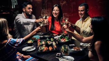 A group of people toasting with wine glasses around a table with various dishes.