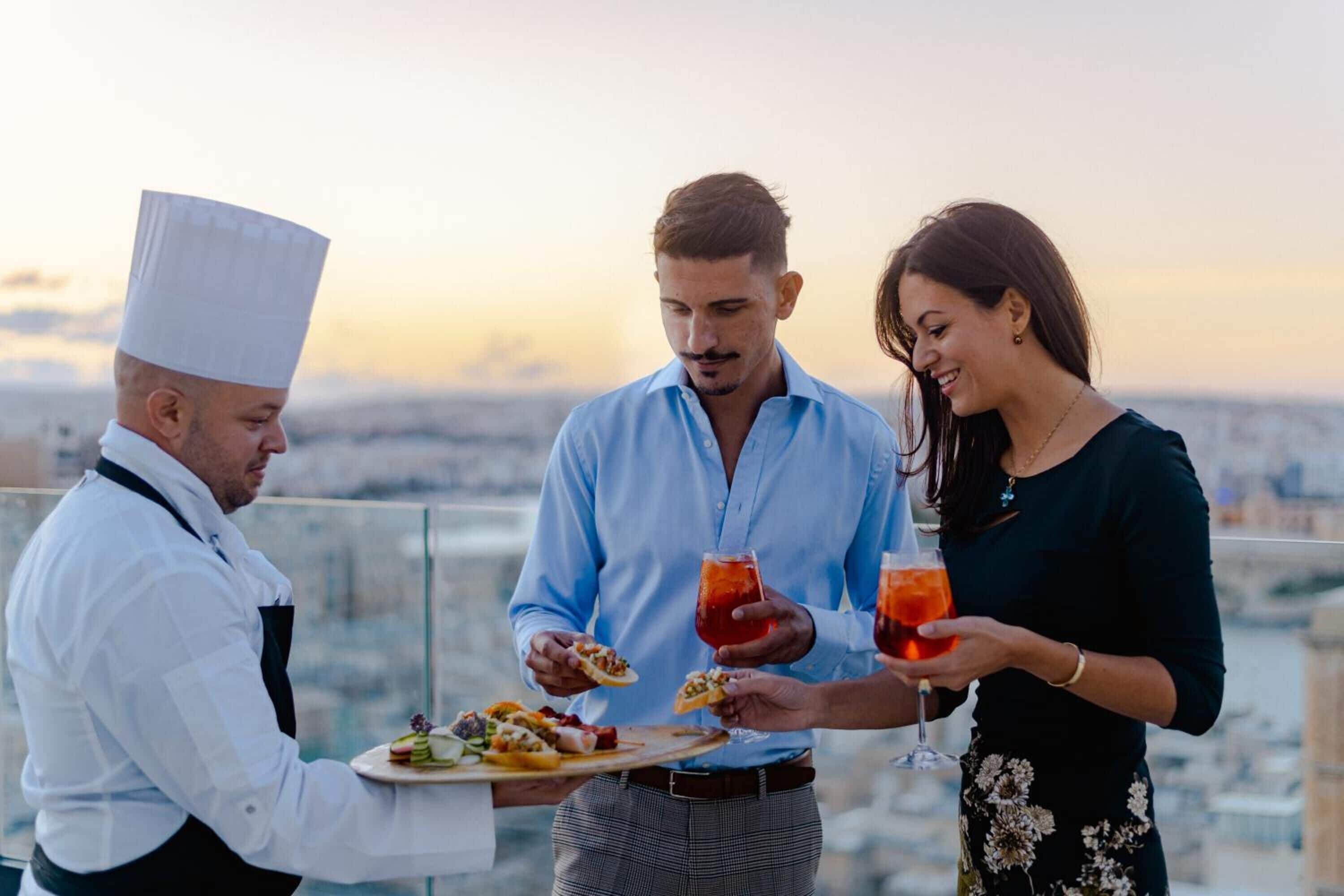 A rooftop dining area with a chef serving food to guests.