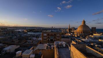 A cityscape with a prominent dome and spires, rooftops with satellite dishes, and a clear sky.