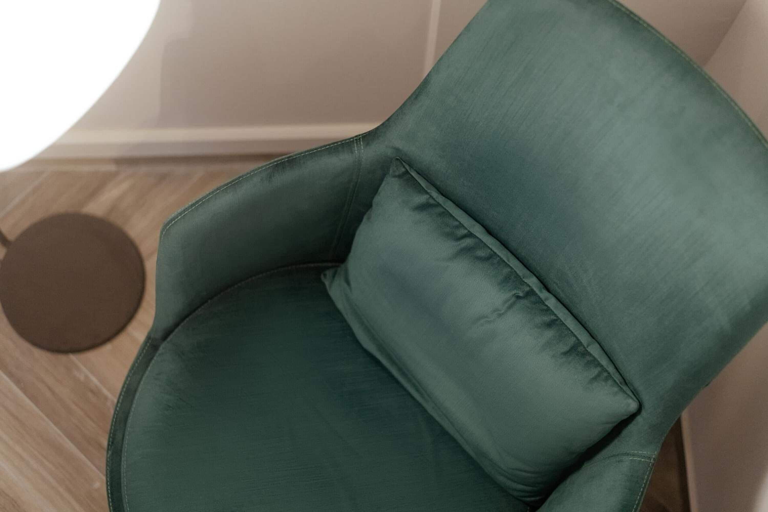 A green upholstered chair with a round cushion.