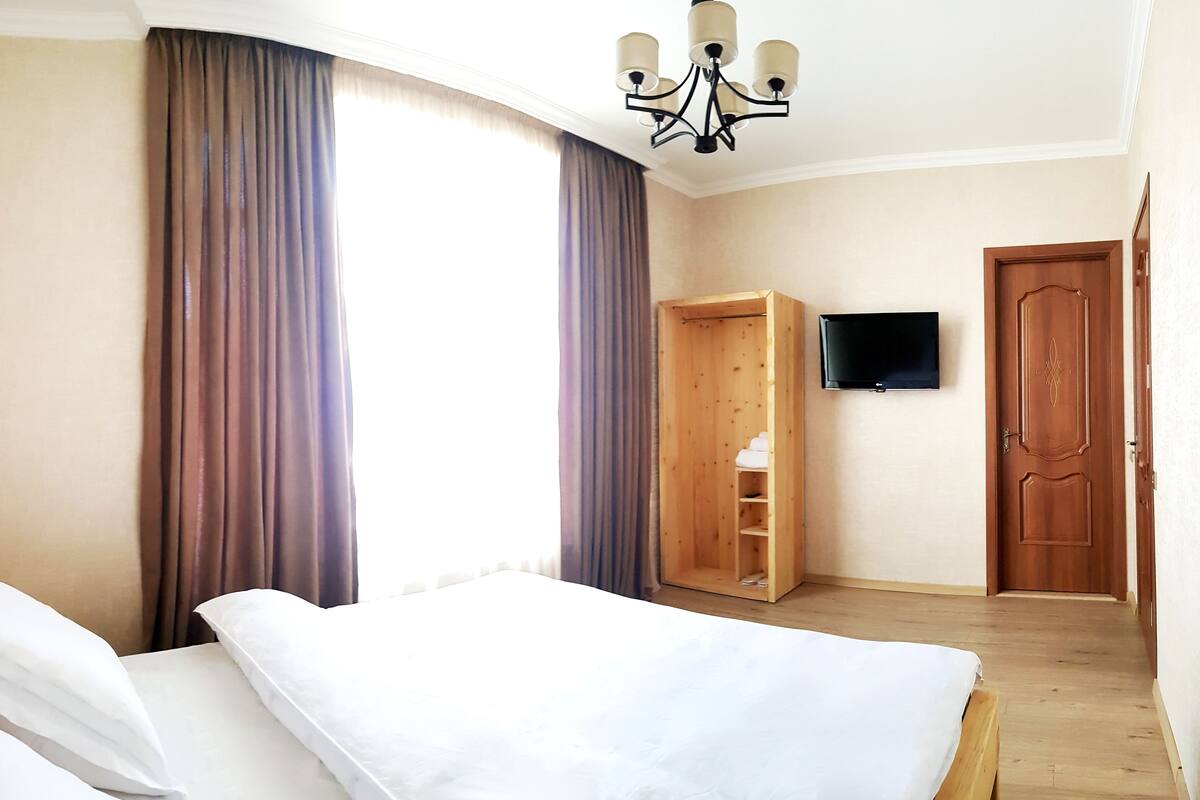 Ein Hotelzimmer mit Bett, Schrank, Fernseher und Tür.