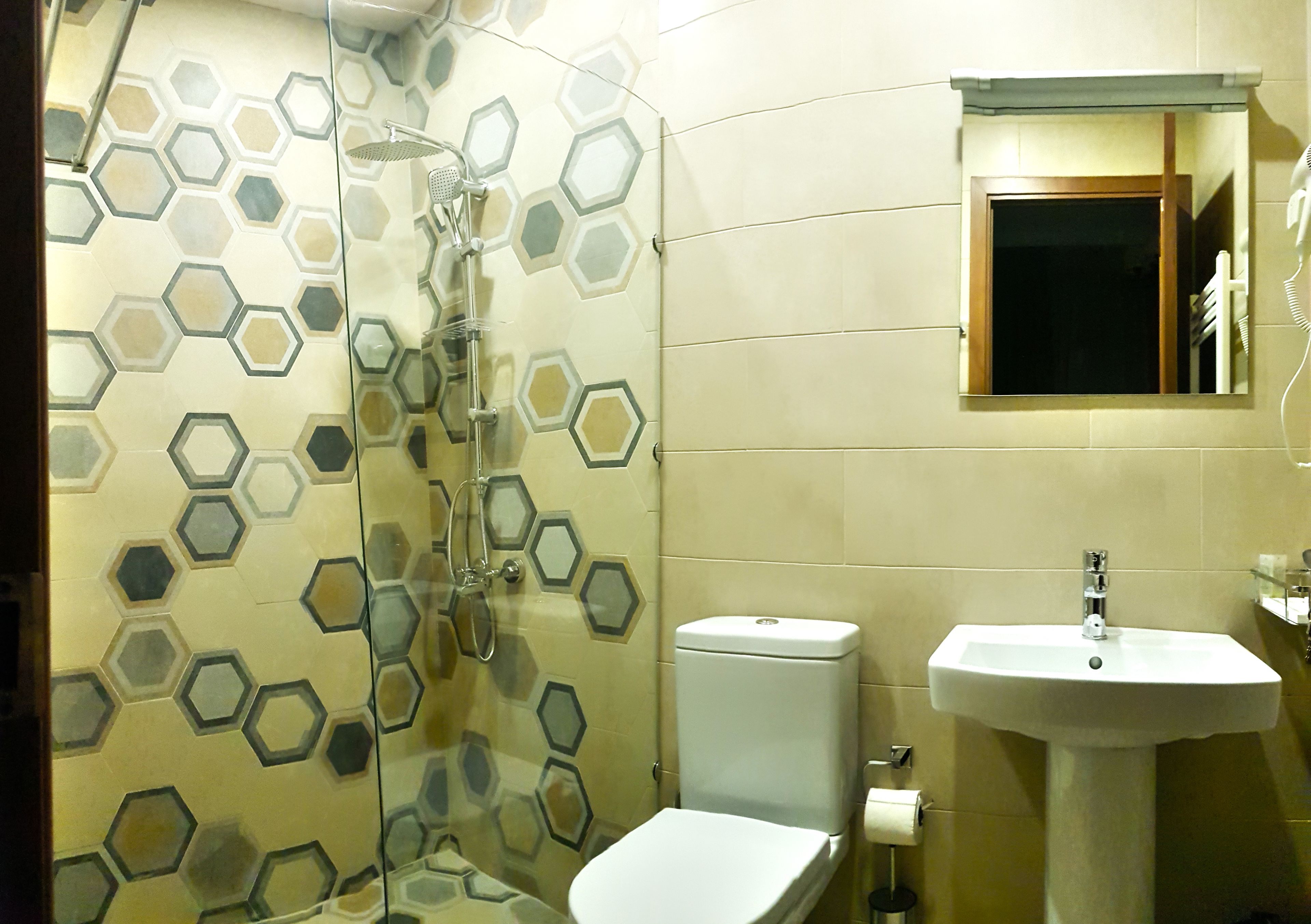 A bathroom with a glass shower enclosure, a toilet, and a sink.