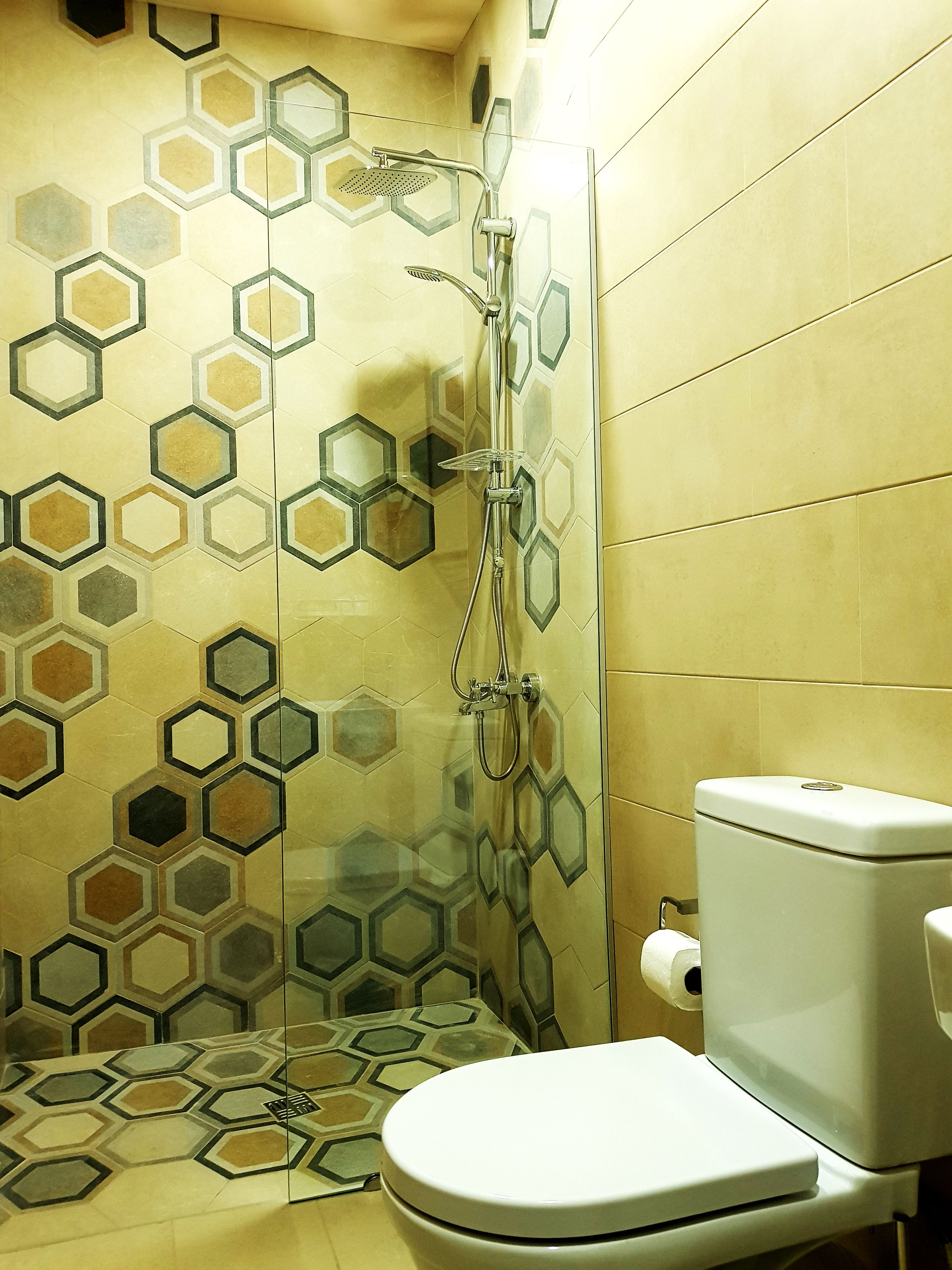 A bathroom with a toilet, shower, and hexagonal patterned tiles.