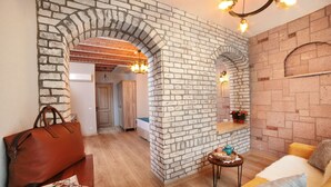 Una sala de estar con pared de ladrillo, muebles de madera y una araña.