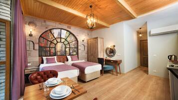 Una habitación acogedora con dos camas, una mesa de comedor con platos y cubiertos, techo de madera y pared de ladrillo con vista a la ventana.