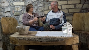 Two people sitting at a rustic wooden table with a stone bowl and a white lantern. - Il Tintore (Tramonti)