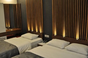 A hotel room with two beds, a wooden headboard with vertical slats, and a bedside table with a phone.