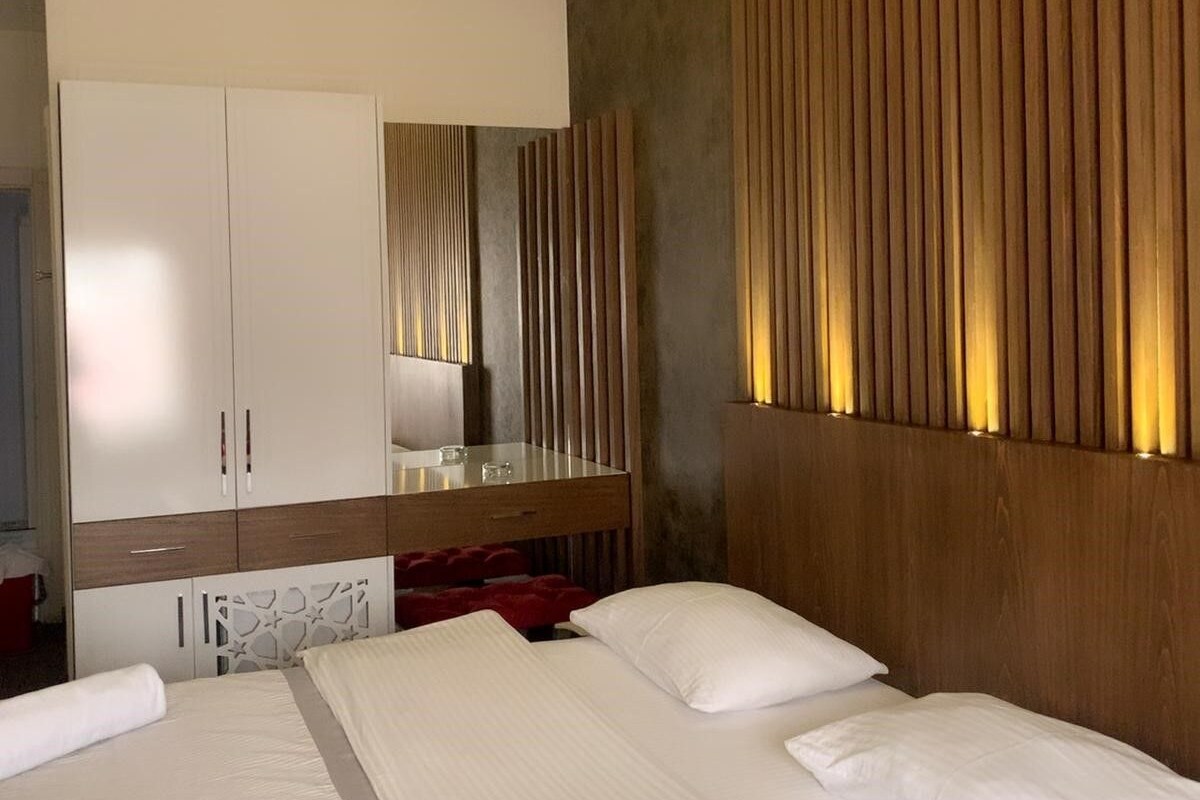 A hotel room with a large bed, a wardrobe, a mirror, and a wooden panel wall.