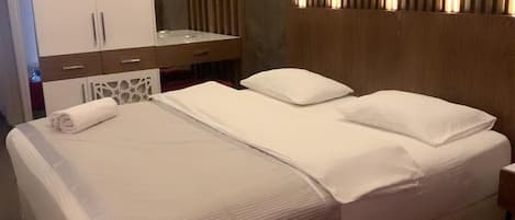 A modern hotel room with a large bed, a bedside table, a mirror, and a wardrobe.