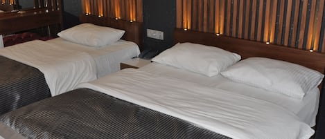 Habitación de hotel con dos camas y cabeceros de madera, además de listones verticales de madera en las paredes.