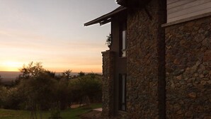 A stone building with a modern design, featuring a large window and a view of the sunset. - Marula House (Naivasha)
