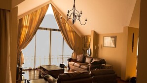 A cozy living room with a leather sofa, a coffee table, and a chandelier. - Marula House (Naivasha)