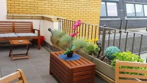 A balcony with a wooden bench, a small table with a potted plant, and a railing. - 3 Beds 2 Baths Penthouse (London)