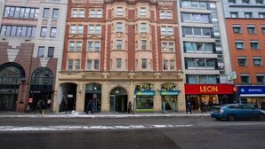A multi-story building with a prominent red storefront labeled "LEON" and a pharmacy across the street. - 3 Beds 2 Baths Penthouse (London)