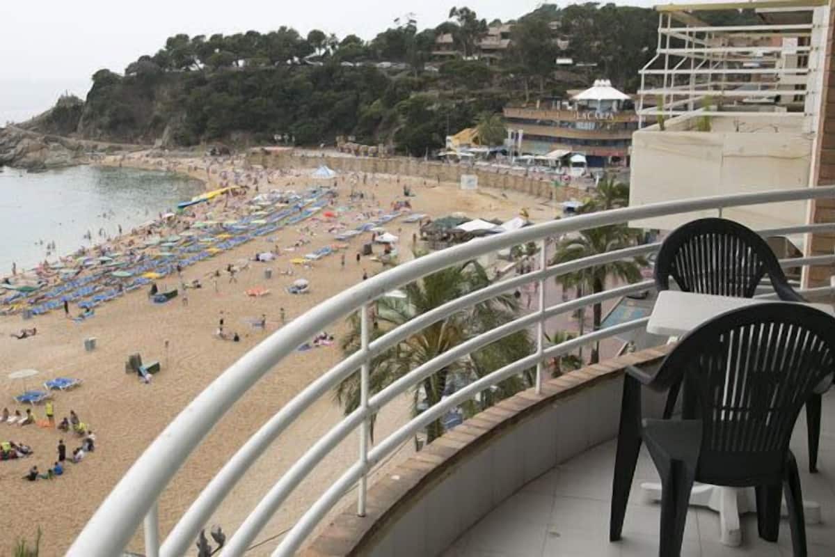 Un balcón con vista a una playa con sombrillas y gente.