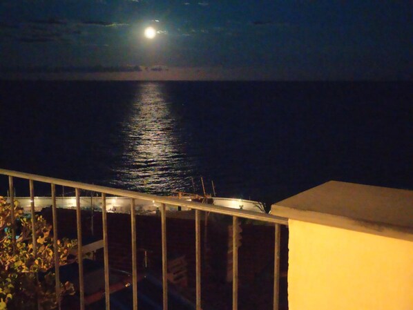 A night view of a balcony overlooking a calm sea with a visible moon reflection on the water. - B&B La Terrazza (Bordighera)