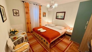 A hotel room with a bed, a chair, a table with a bouquet of flowers, and a painting on the wall. - Rooms Center of Trogir (Trogir)
