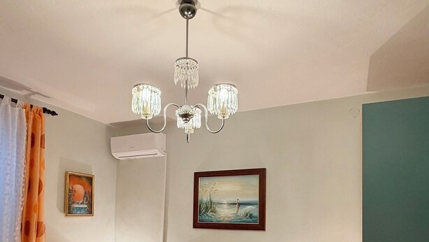 A hotel room with a bed, a nightstand, a lamp, a painting, and an air conditioning unit. - Rooms Center of Trogir (Trogir)