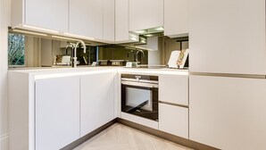 Une cuisine moderne avec des meubles blancs, un four encastré et un plan de travail doté d’un évier et d’une cuisinière.