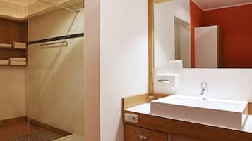 A modern bathroom with a glass shower, a white sink, and a wooden vanity.
