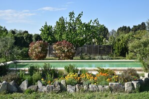 A swimming pool surrounded by a garden with various plants and flowers. - Vintage houseboat rider ... (Saint-Rémy-de-Provence)