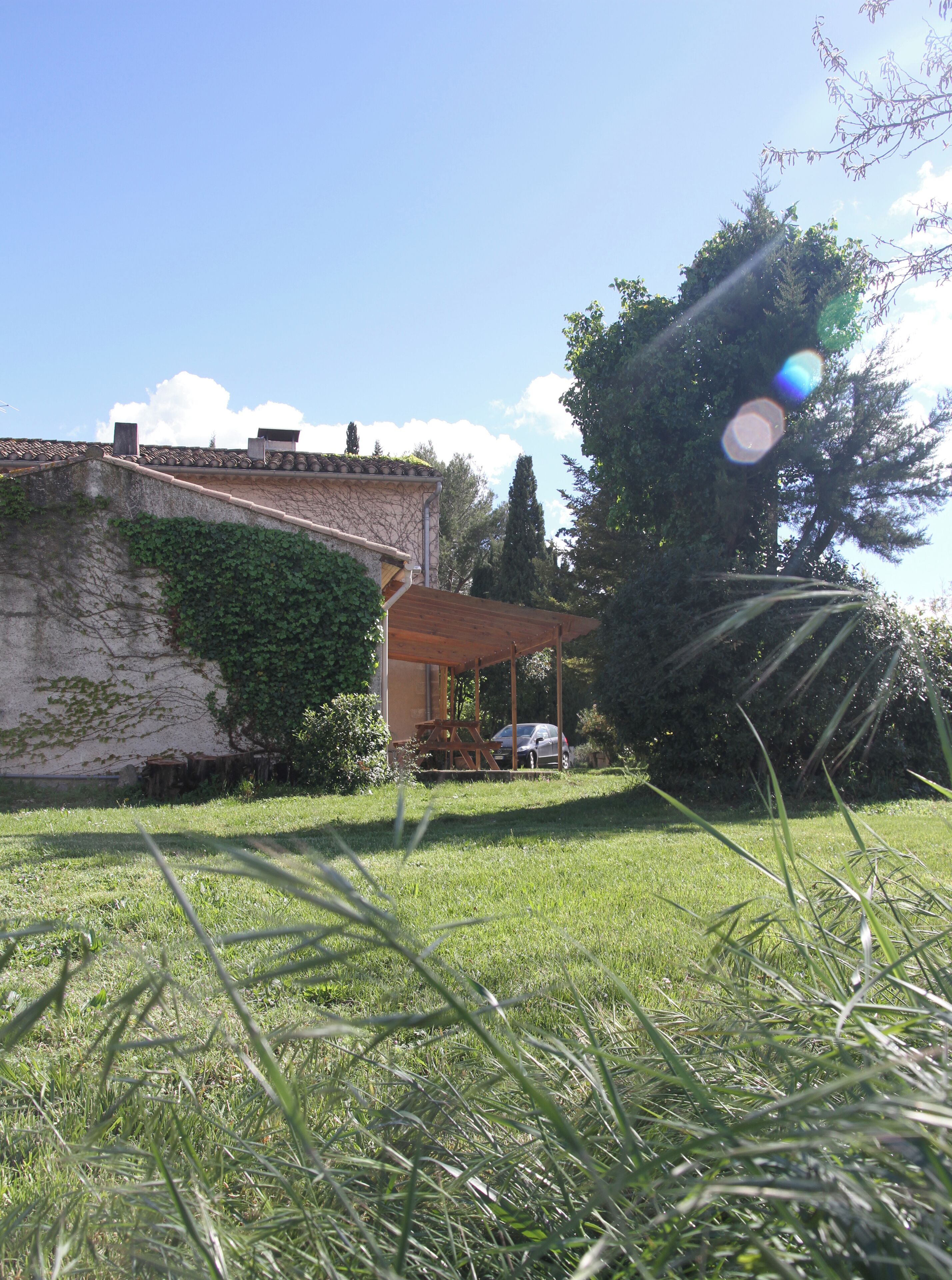 Une maison avec un patio couvert et une voiture garée devant.