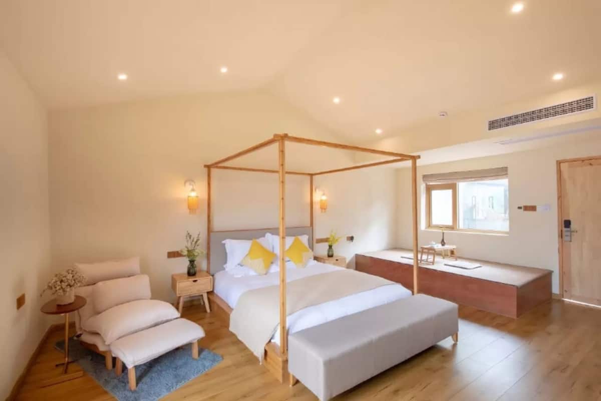 Ein geräumiges Schlafzimmer mit einem Himmelbett, einer Bank und einem Nachttisch mit einer Vase.