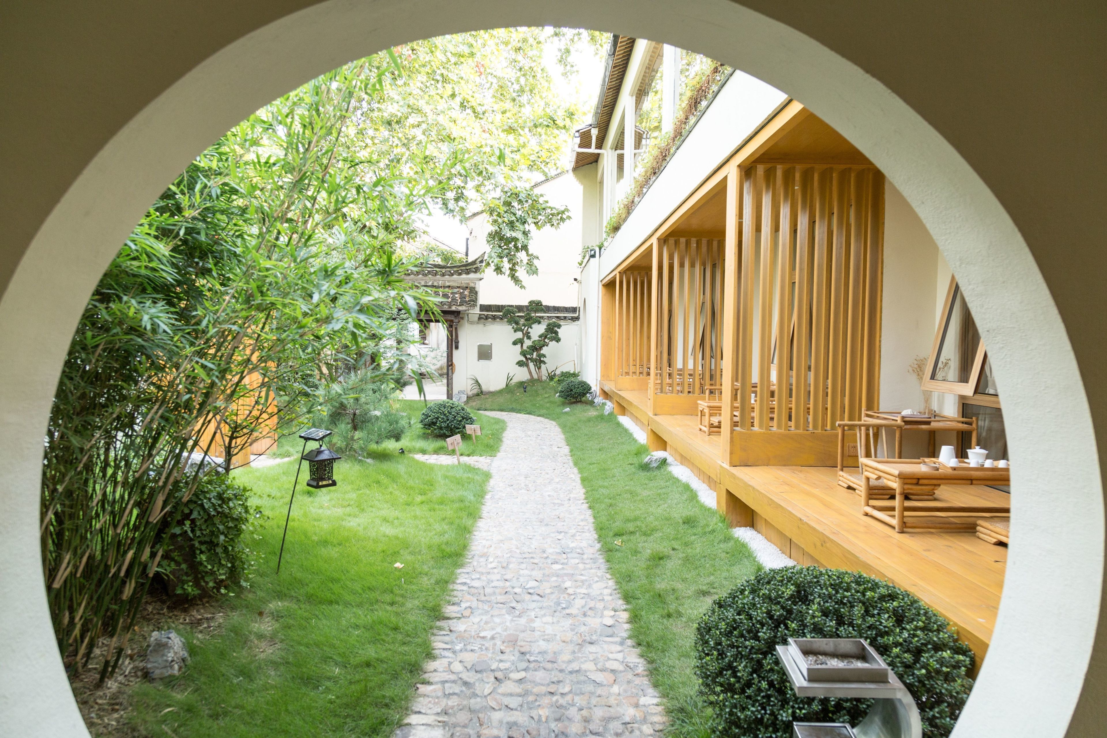 Un cortile con un vialetto in pietra, un pontile in legno e vegetazione.