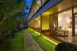 A modern building with a well-maintained garden, a stone pathway, and a cozy interior with a bed and seating area. - Qing Zhi Wu Lu hostel (Jinhua)