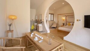 Une chambre d’hôtel moderne avec une table à manger en bois, un lit à baldaquin et un téléviseur fixé au mur.