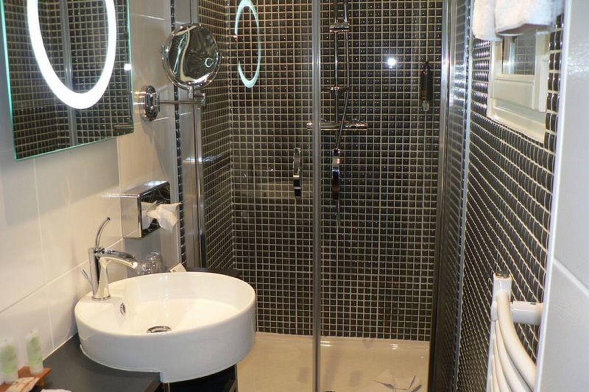A bathroom with a white sink, a glass shower enclosure, and a mirror with a circular frame.