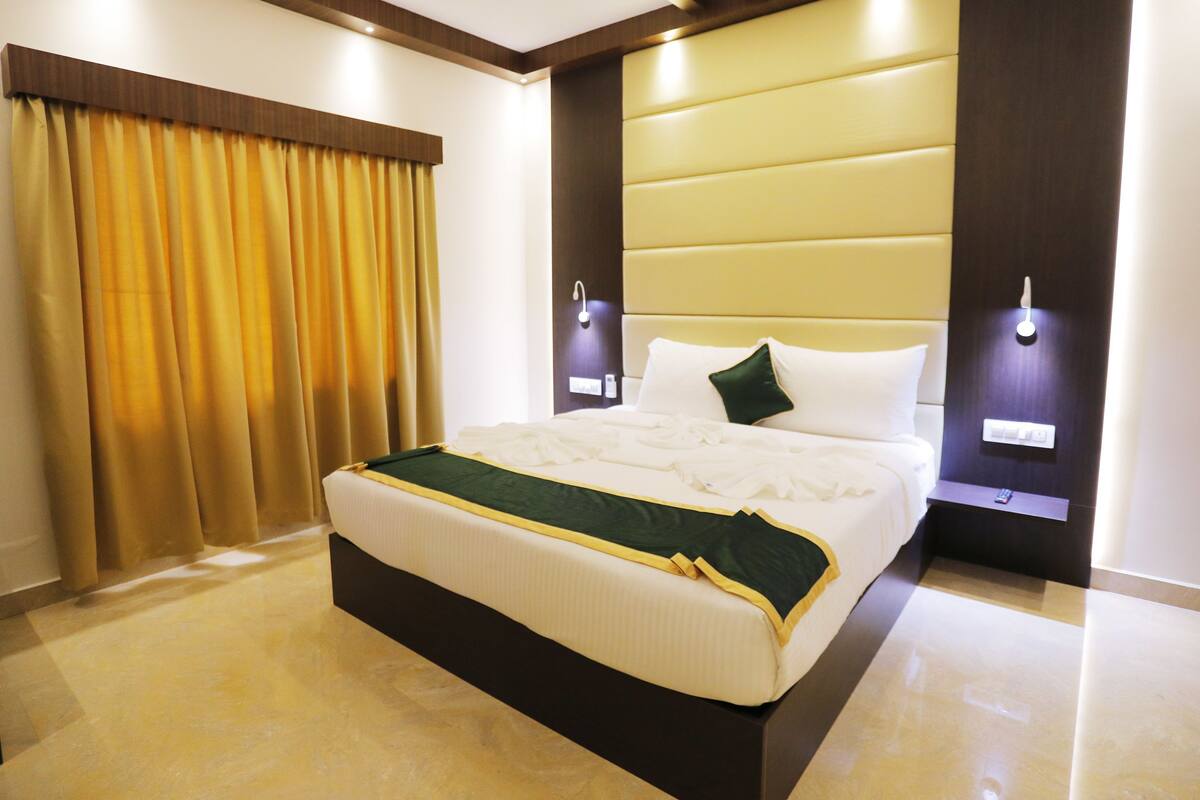 A hotel room with a large bed, a headboard, a bedside table, and a wall-mounted light.