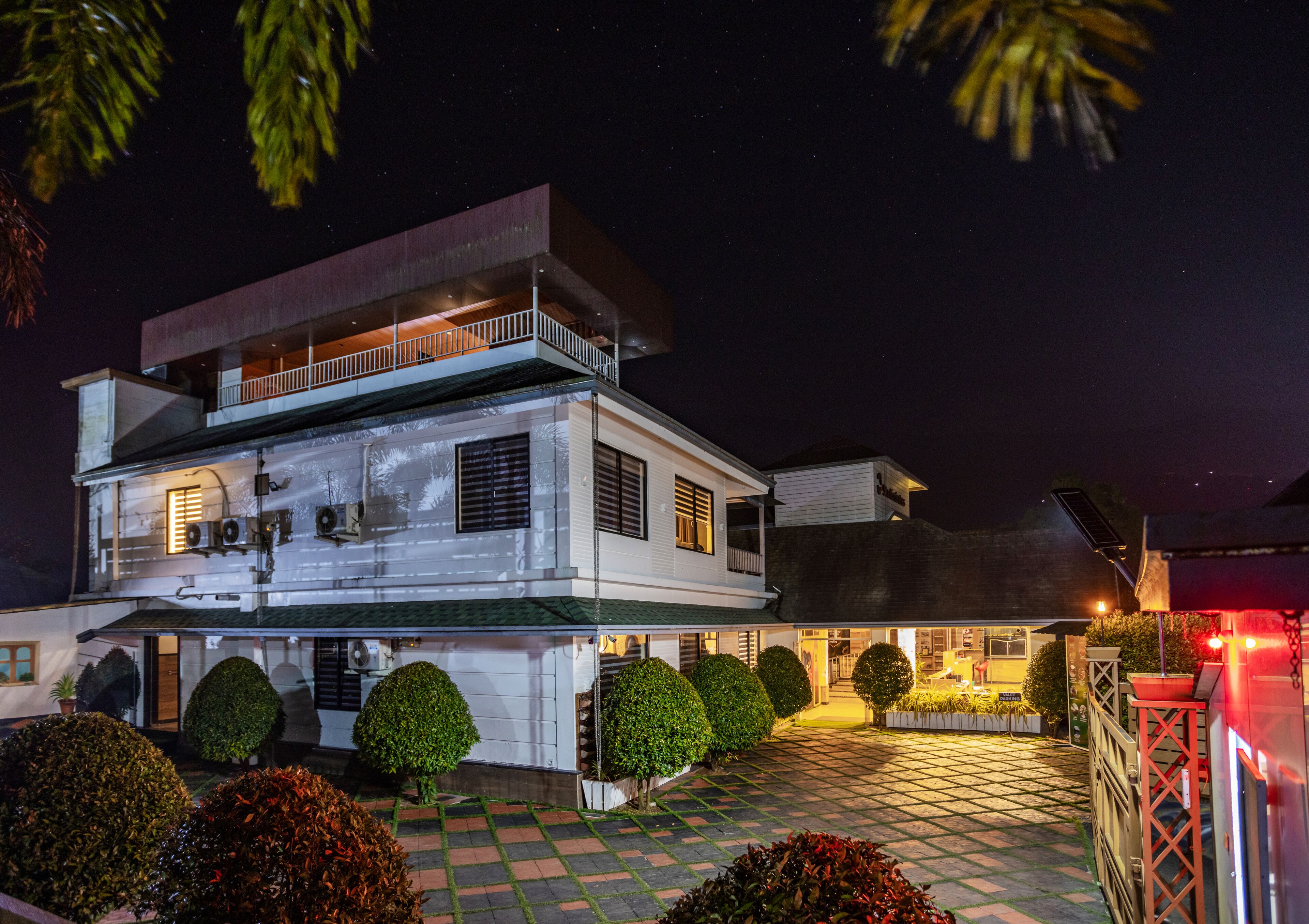 A two-story building with a balcony, a covered outdoor area, and a paved driveway.