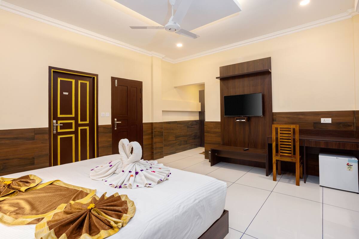 A hotel room with a bed, a desk, a television, and a small refrigerator.