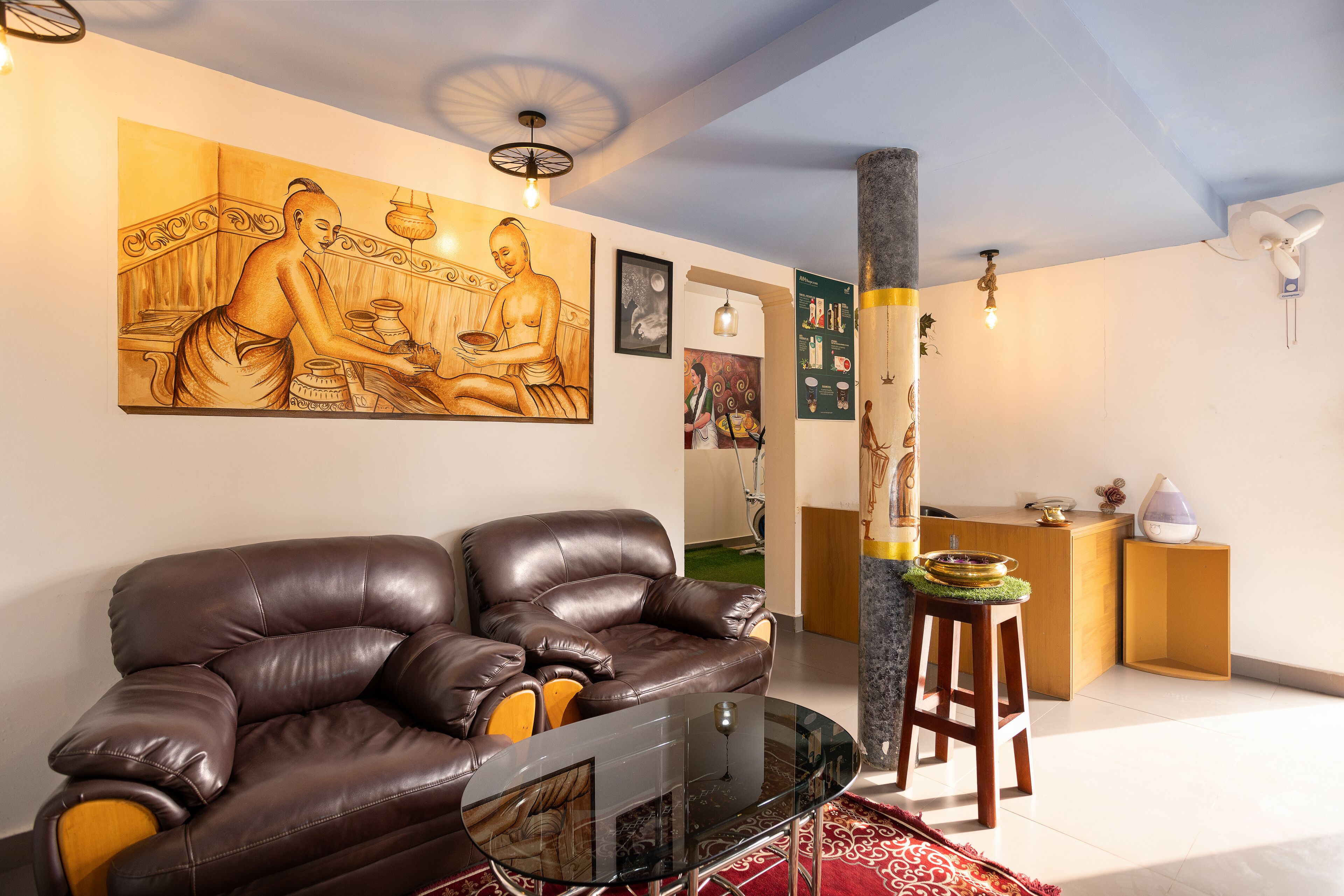 A living room with a brown leather sofa, a glass coffee table, and a large painting on the wall.