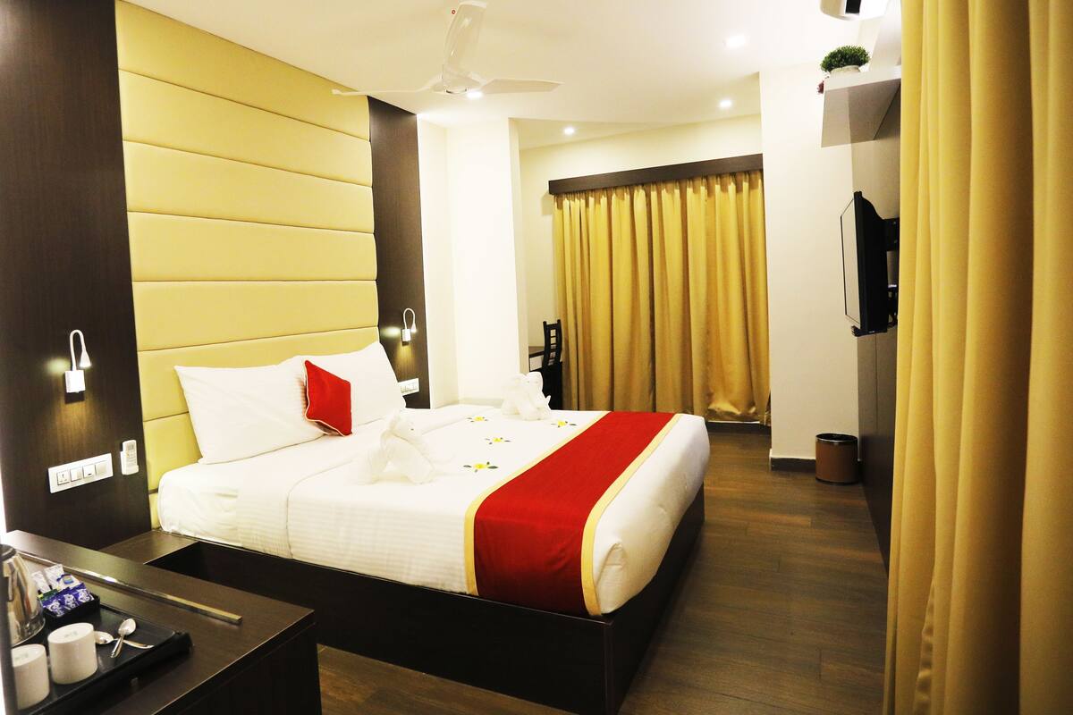 A hotel room with a bed, bedside table, and a television.