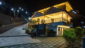 Una casa moderna de dos pisos con balcón, camino de entrada pavimentado y entrada bien iluminada.
