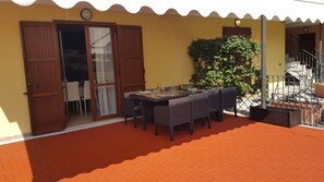 An outdoor dining area with a table set for two, a wooden door, and a yellow wall. - Superb apartment in the center of Moniga with WIFI (Moniga del Garda)