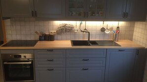 Una cucina moderna con mobili grigi, un lavandino nero e un forno integrato.