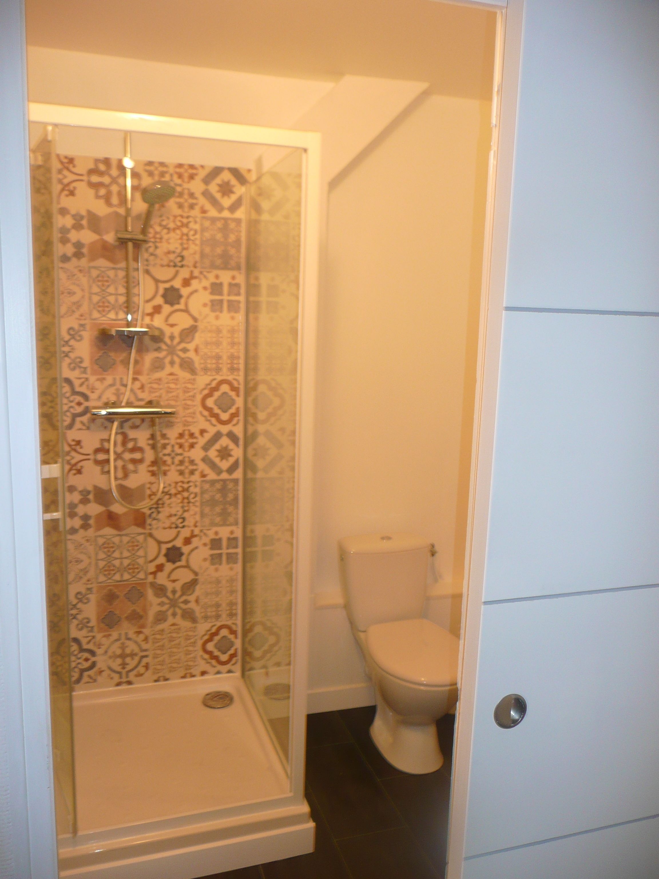 Et badeværelse med brusekabine, toilet og et hvidt skab.