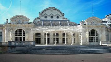 A grand building with a large central dome, arched windows, and a covered entrance area.
