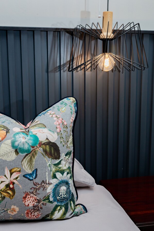 A bed with a floral pillow and a modern pendant light fixture.