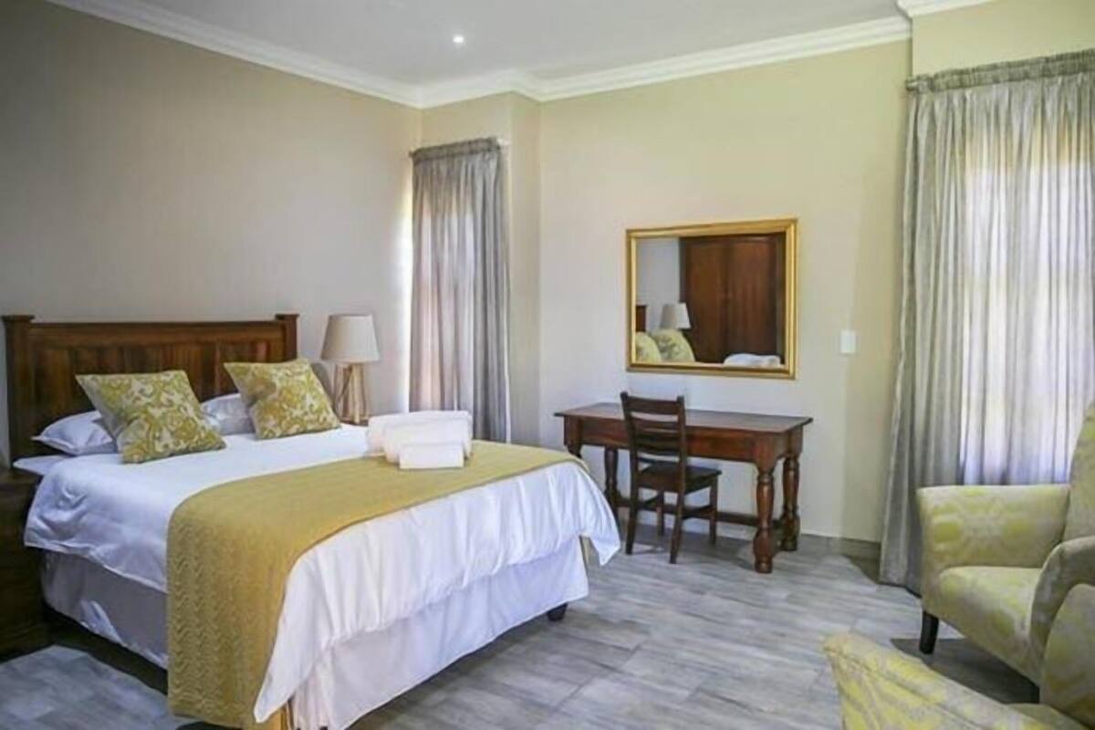 A hotel room with a bed, a desk, a chair, and a mirror.