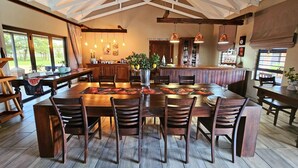 A spacious dining area with a high ceiling and wooden beams, featuring a large table and multiple chairs. - 2 Owls Guesthouse (Potchefstroom)