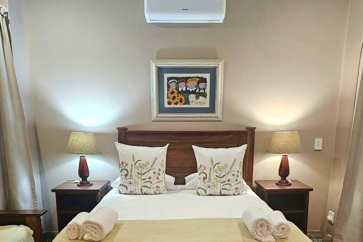 A hotel room with a bed, two nightstands, a framed picture above the bed, and a window with curtains.