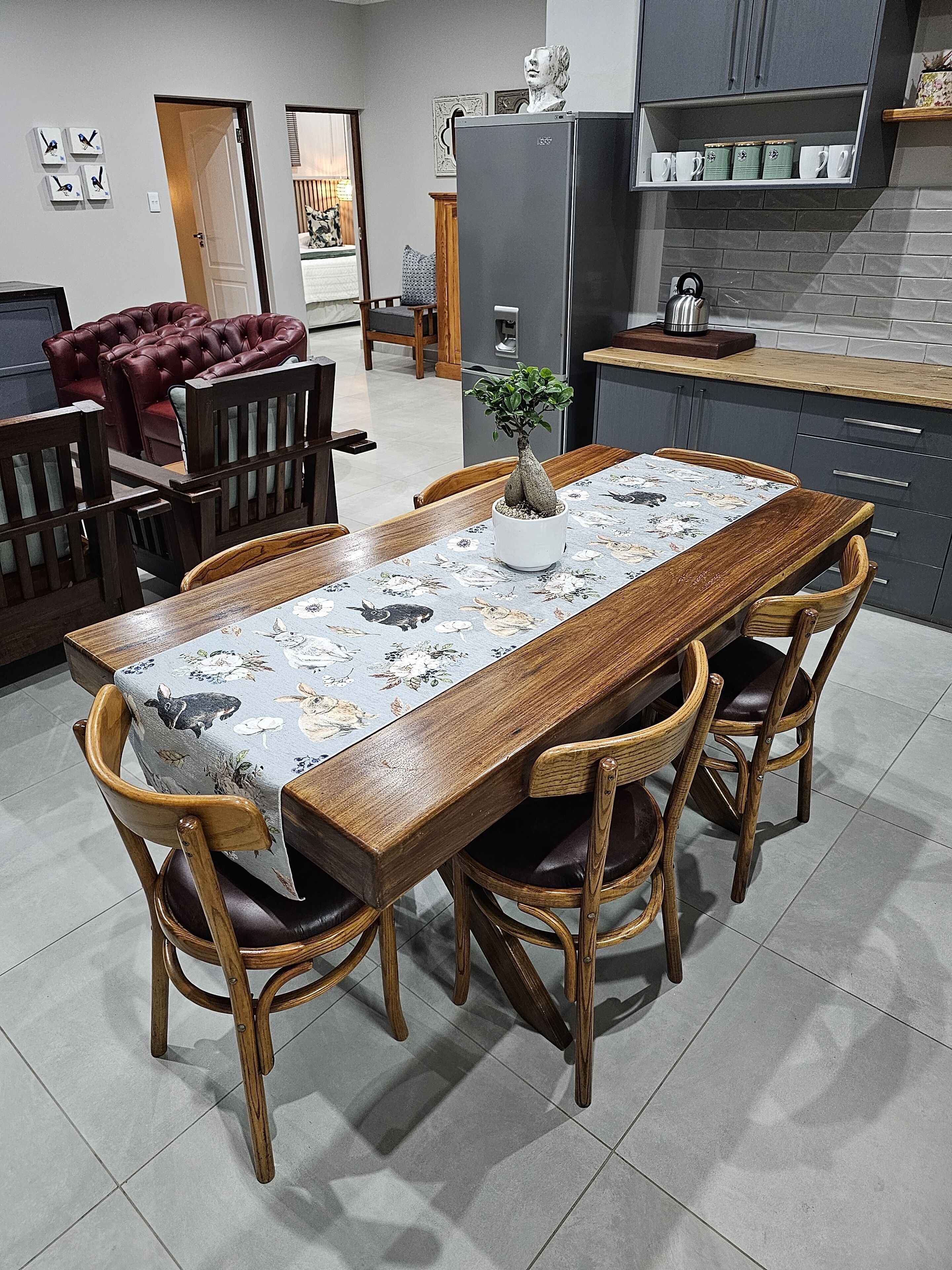 A dining area with a wooden table, wicker chairs, and a floral tablecloth.